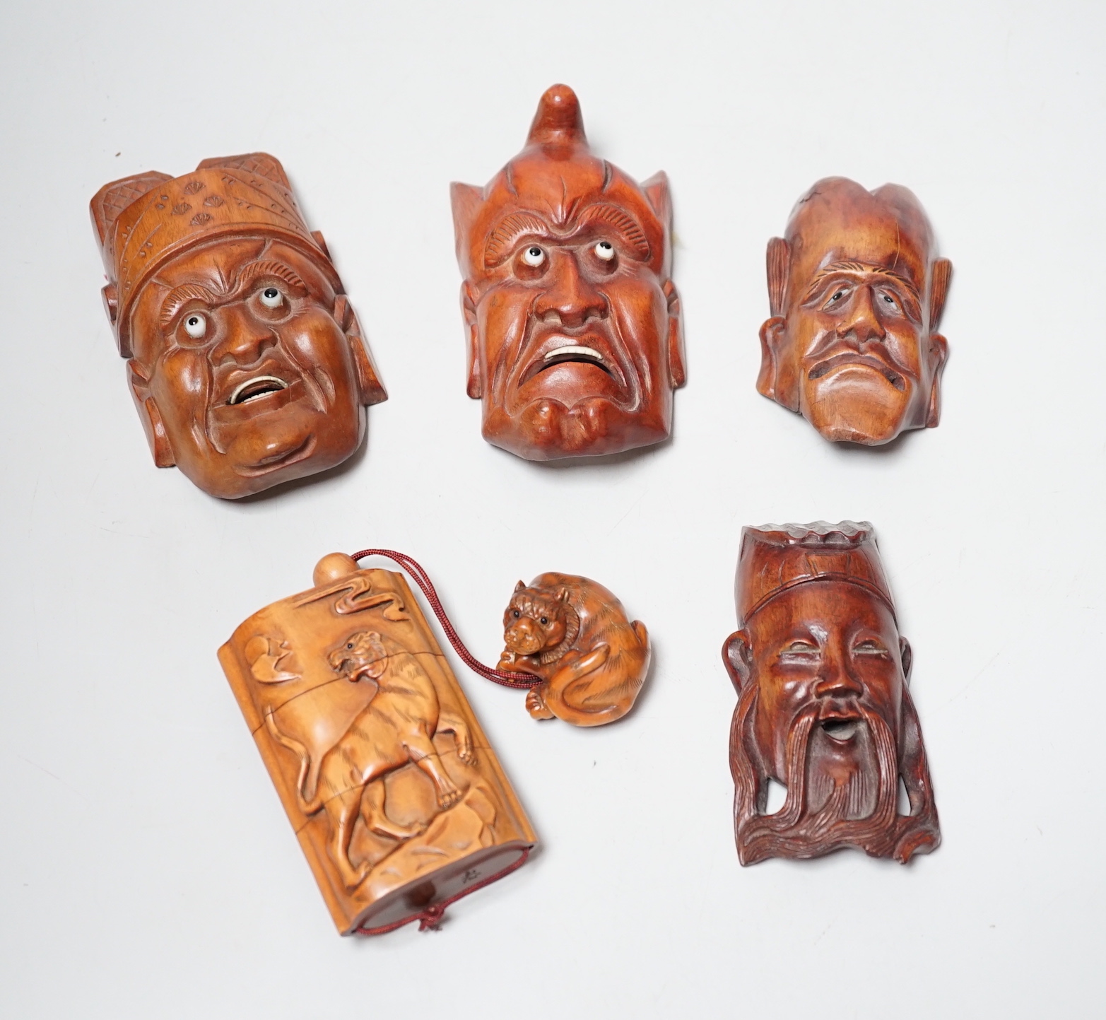 A group of hardwood models of noh masks and a similar inro, 9cm and netsuke